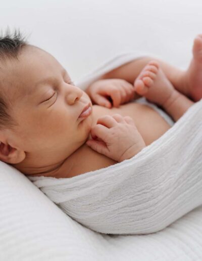 Zartes Neugeborenen-Fotoshooting: Ein schlafendes Baby in natürlichem Licht, liebevoll inszeniert für zeitlose Babyfotos.