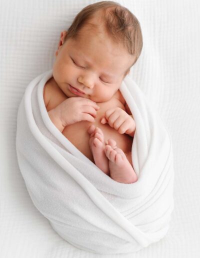 Newborn-Shooting: Ein verschlafenes Lächeln, das die ersten Momente des Babys zeigt.